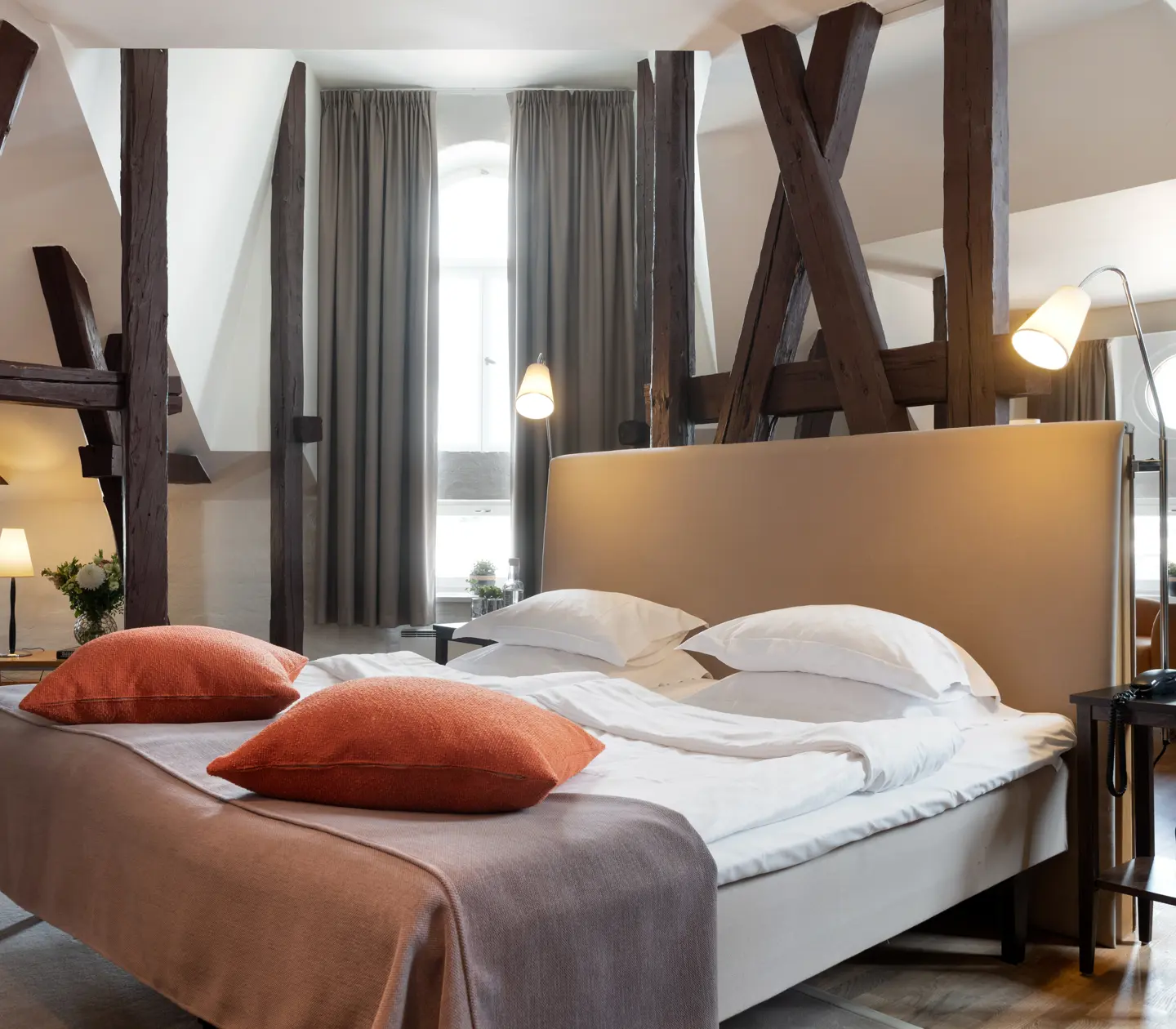 Bright suite with bed, large window and wooden beams from the ceiling