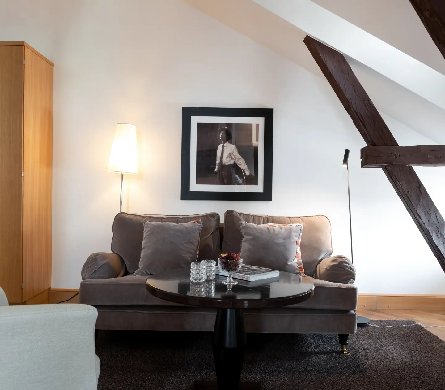 Bright suite with sofa, wardrobe and wooden beams from the ceiling