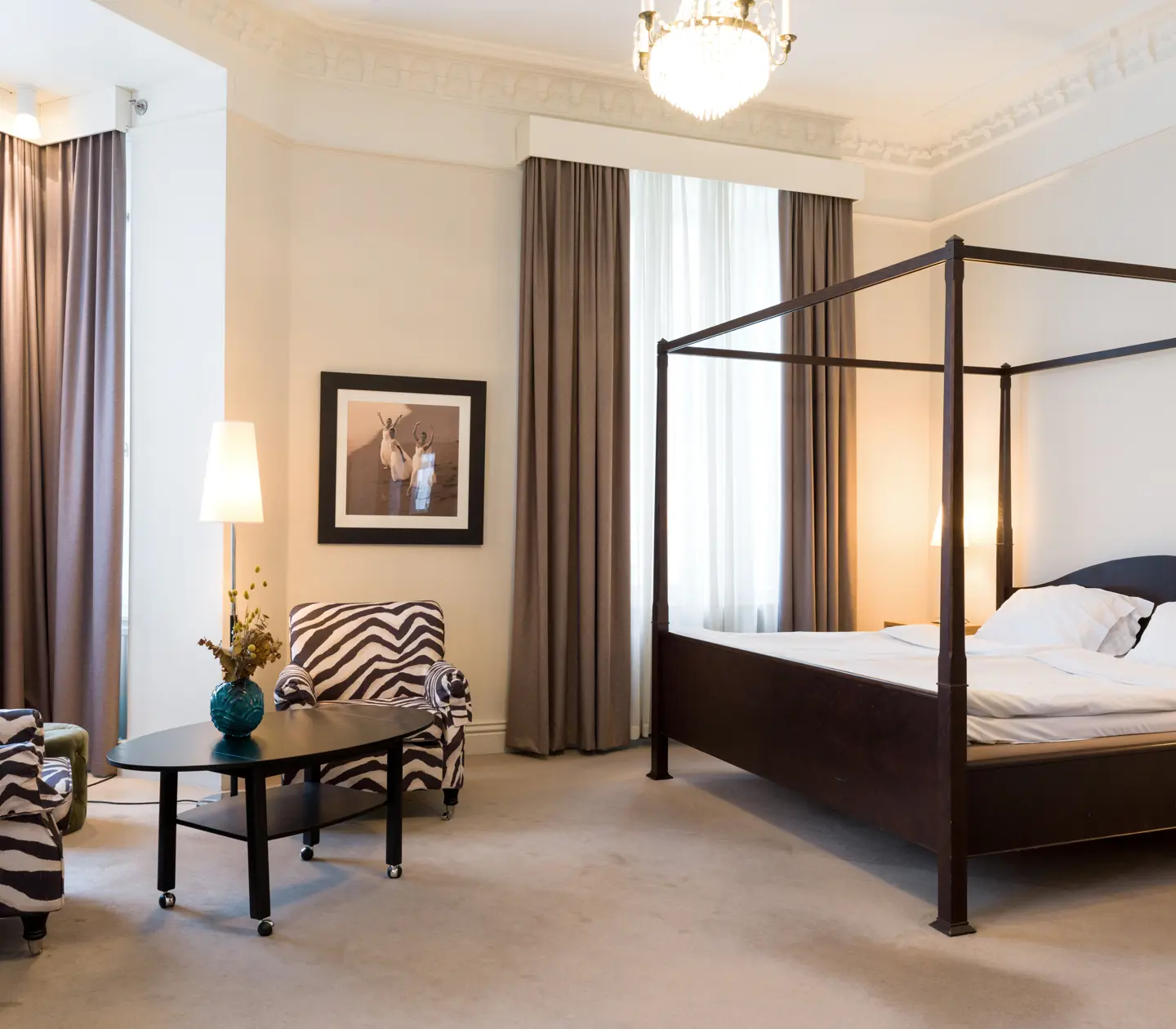 Bright suite with bed, wooden frame and zebra-patterned armchairs
