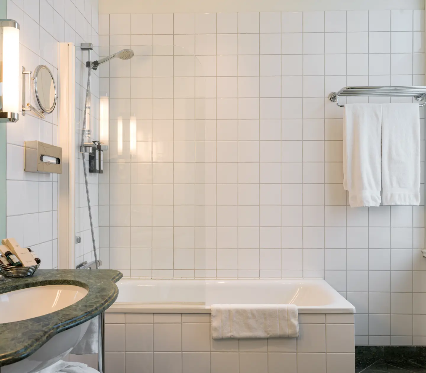 Bright bathroom with bathtub, green sink and towels