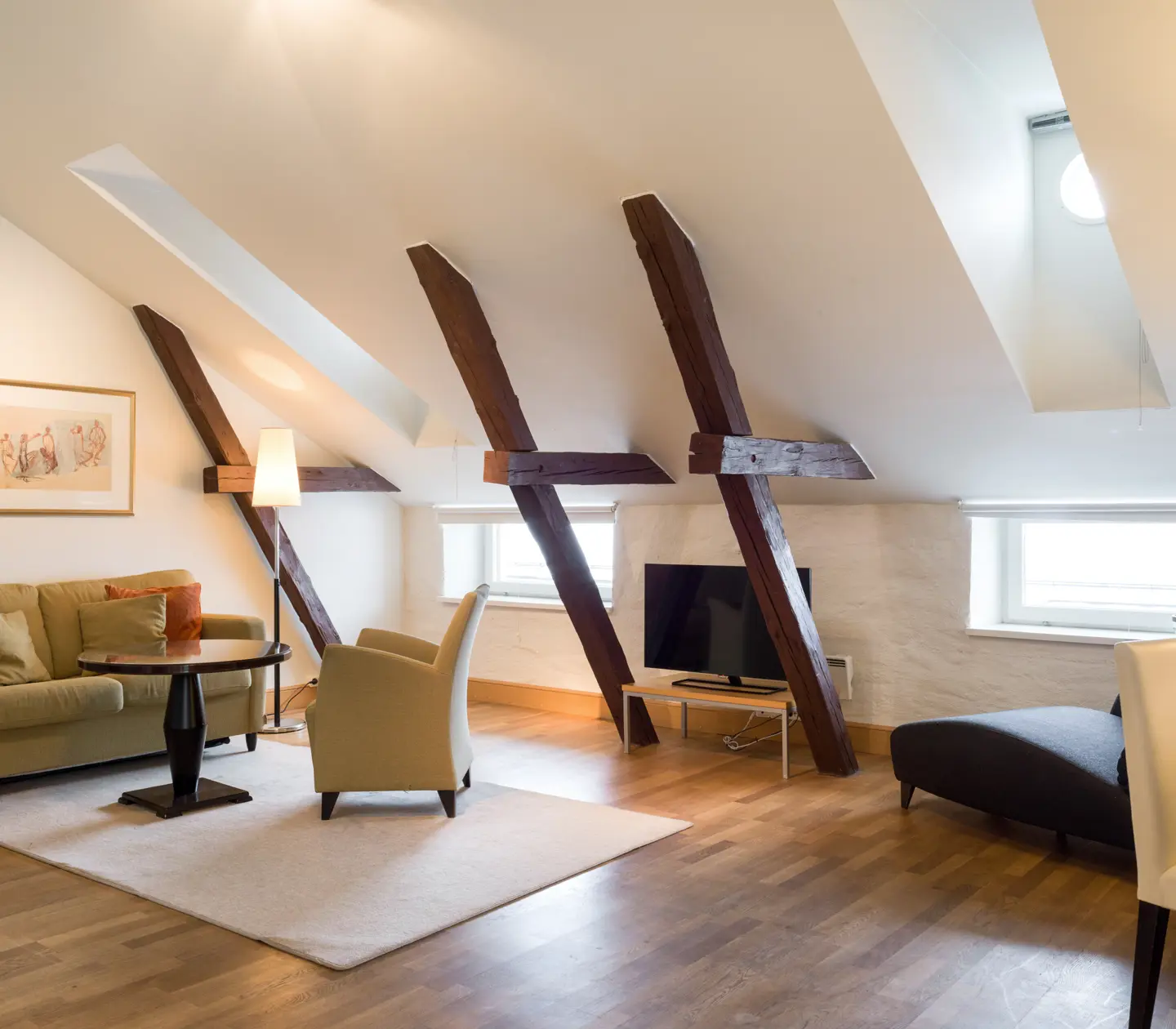 Bright suite with wooden beams from the ceiling, sofa group and TV
