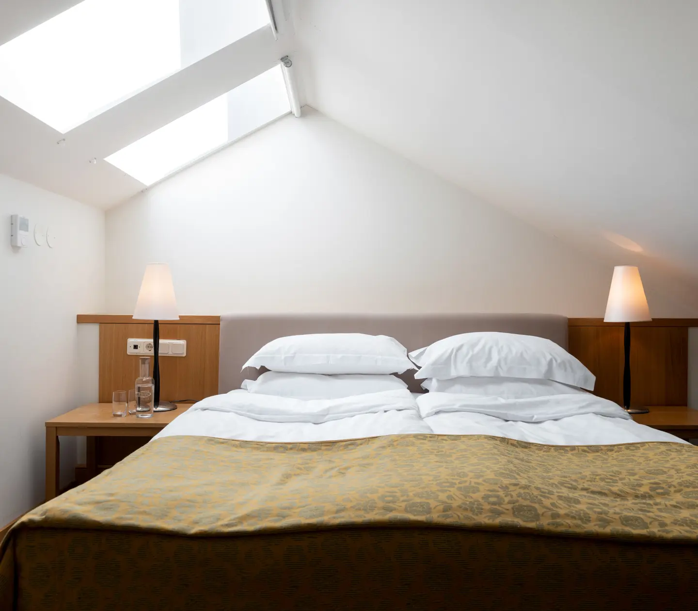 Bright suite with bed, skylight and bedside lamps