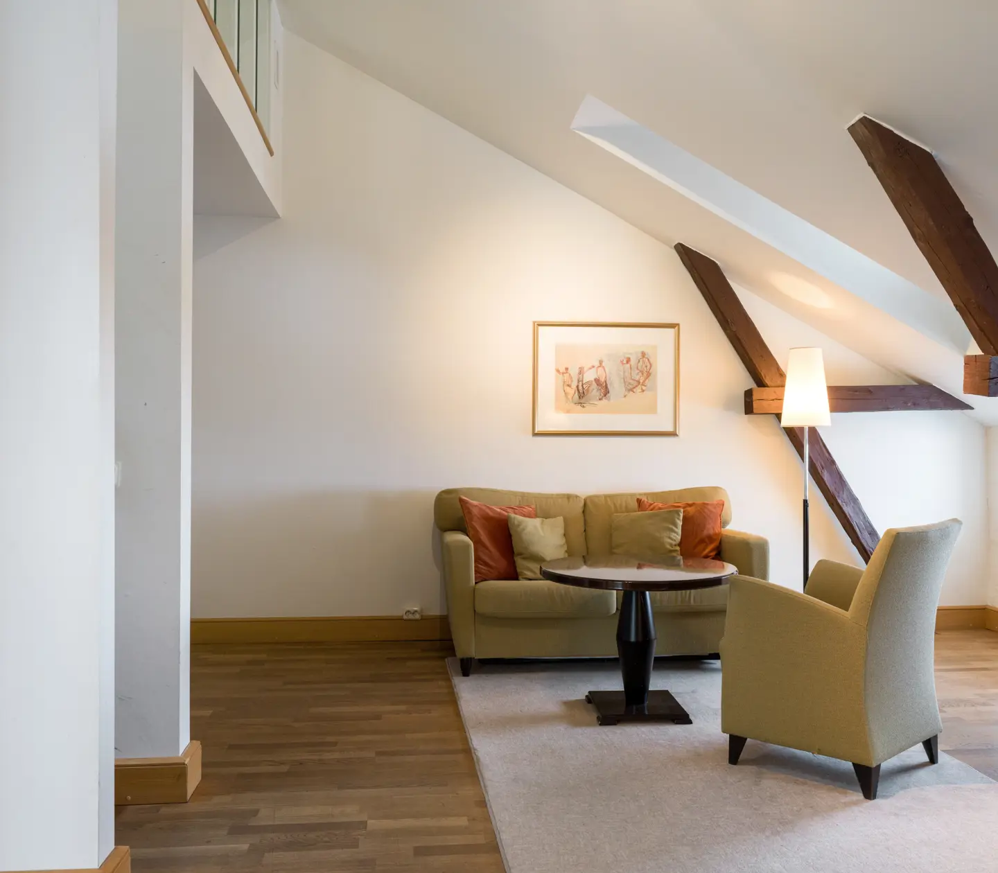 Bright suite with wooden beams from the ceiling, sofa group and painting
