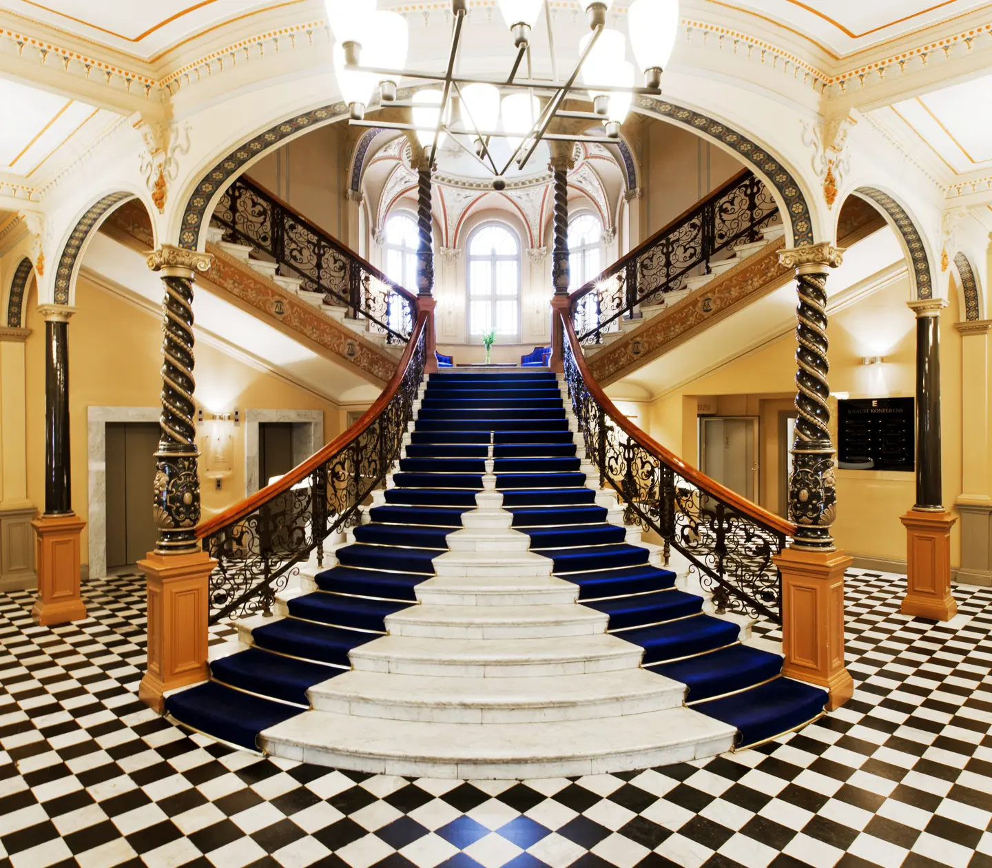 Fancy staircase with lots of decorations in hotel lobby with checkerboard floor