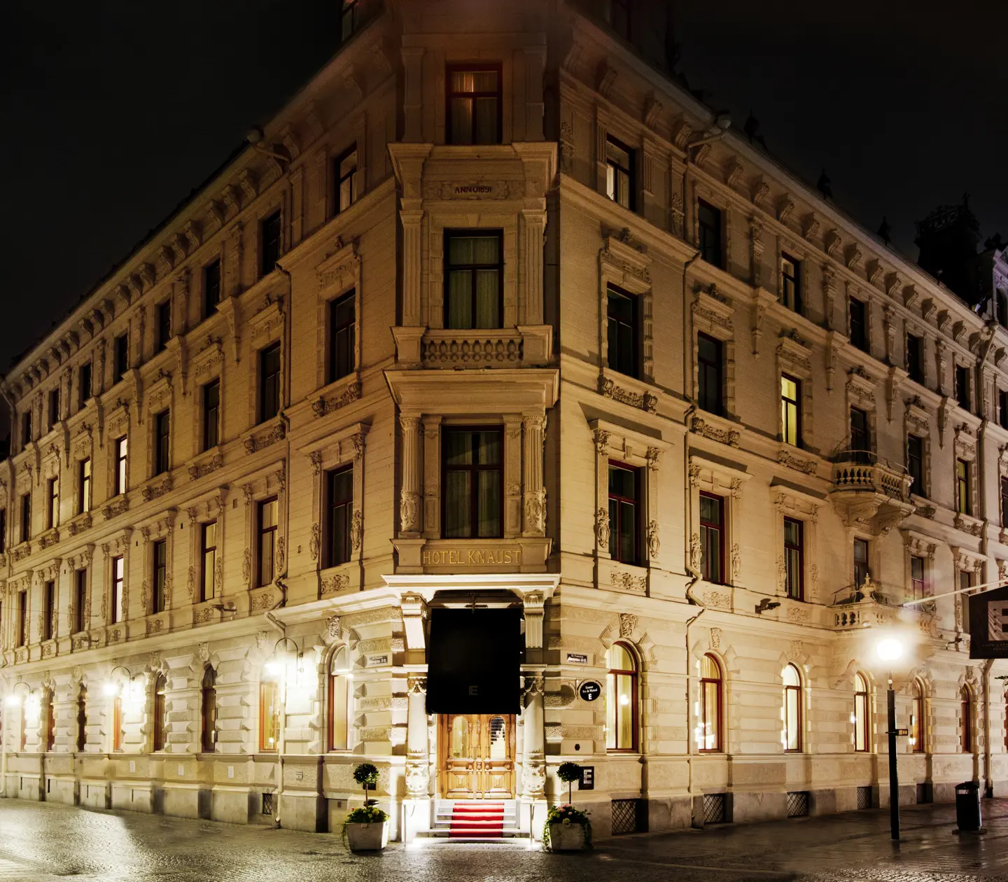 The elegant white facade of the Elite Hotel Knaust at dusk