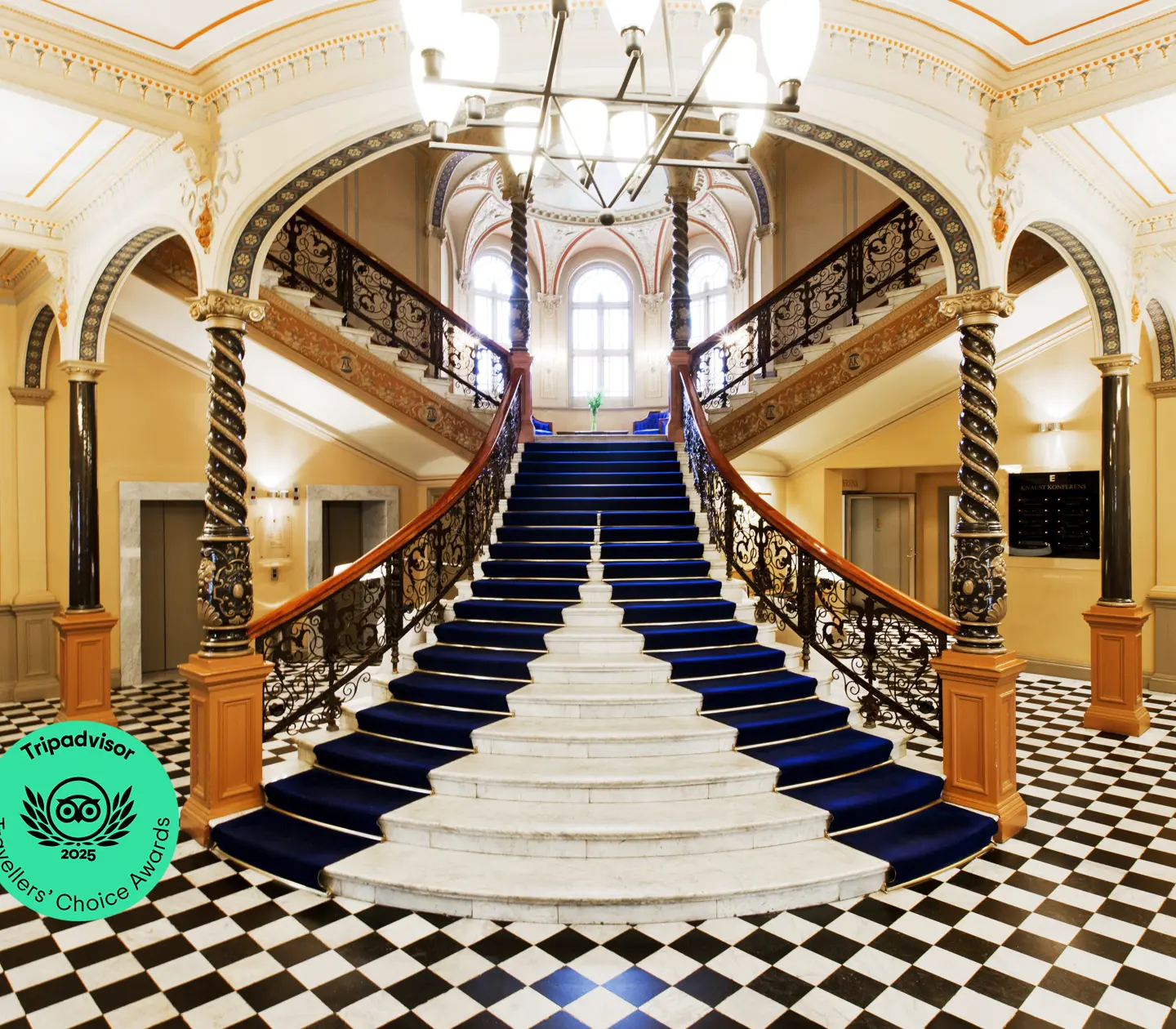 Fancy staircase with lots of decorations in hotel lobby with checkerboard floor