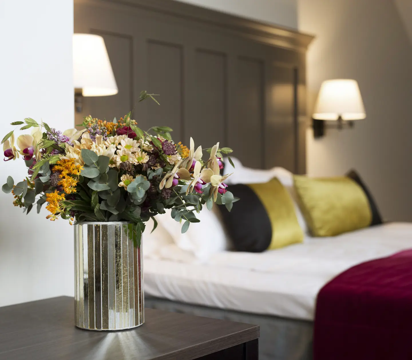 Bright hotel room with bed, flower bouquet and bedside lamps