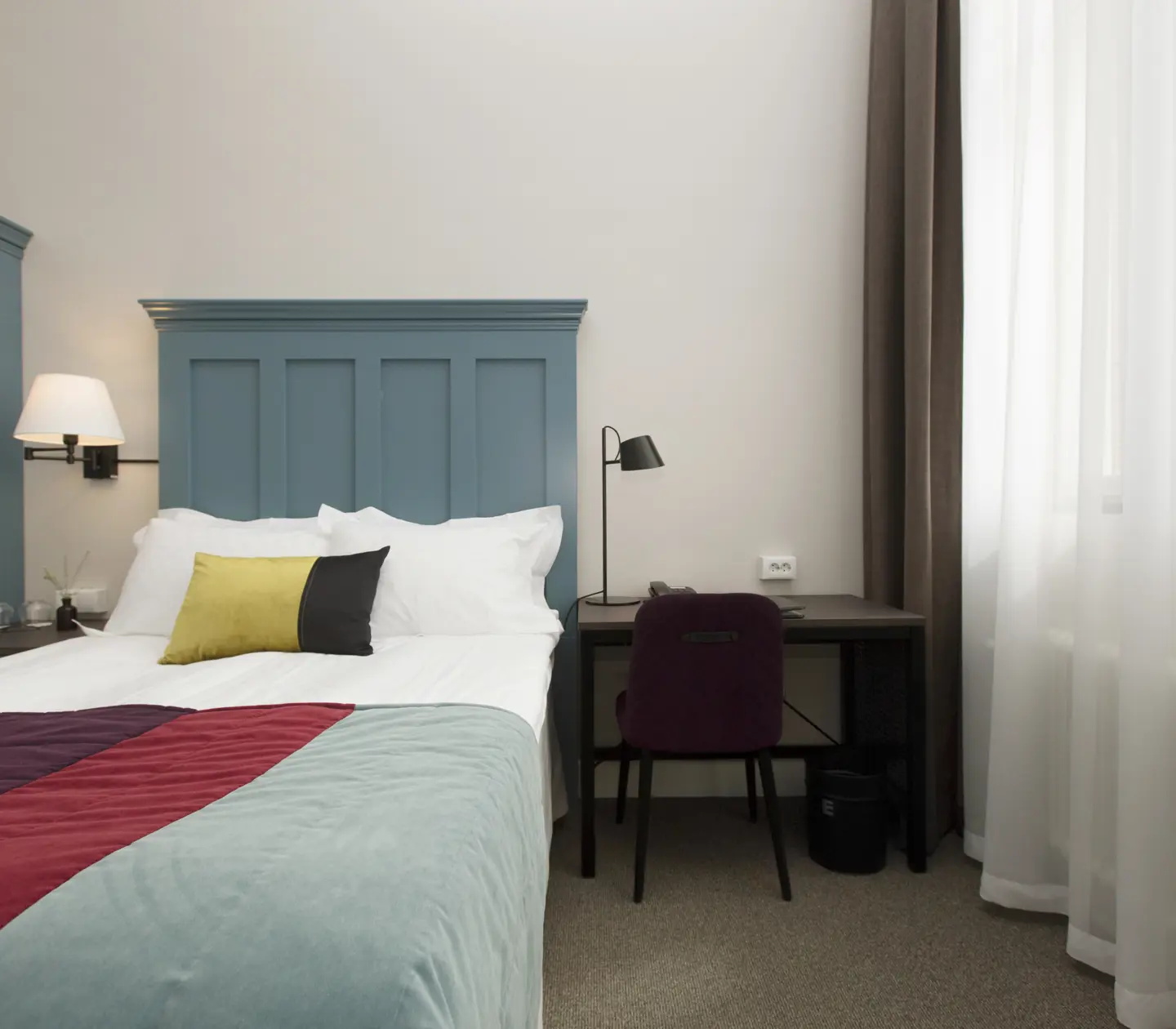 Bright hotel room with bed, flower bouquet and bedside lamps
