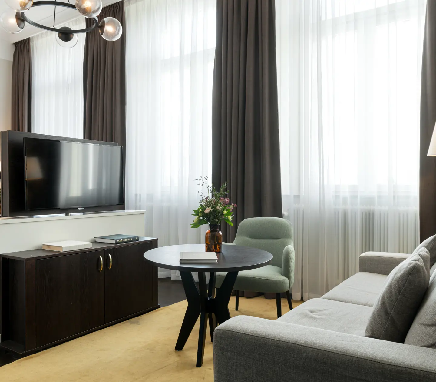 Bright hotel room with sofa group, TV and large windows