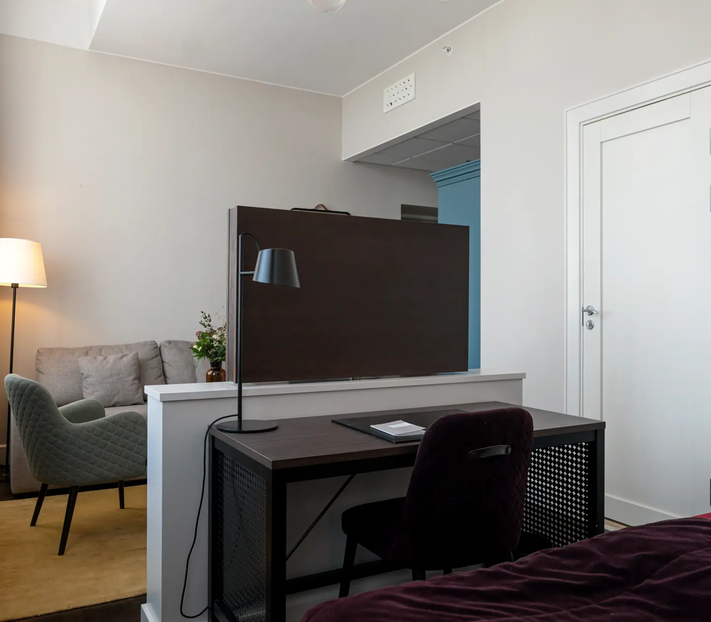 Bright hotel room with sofa group, TV and desk
