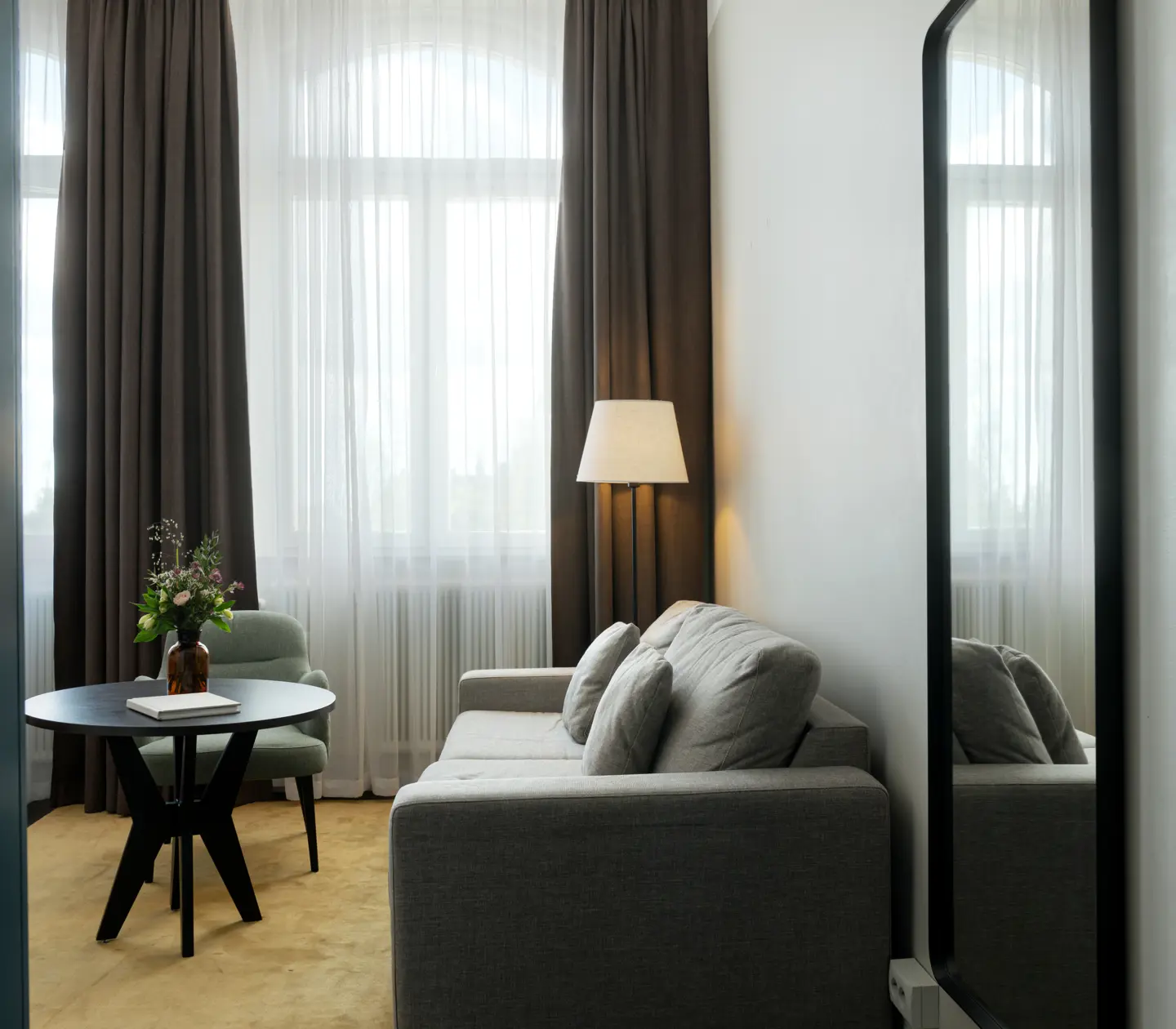 Bright hotel room with sofa group, mirror and wardrobe
