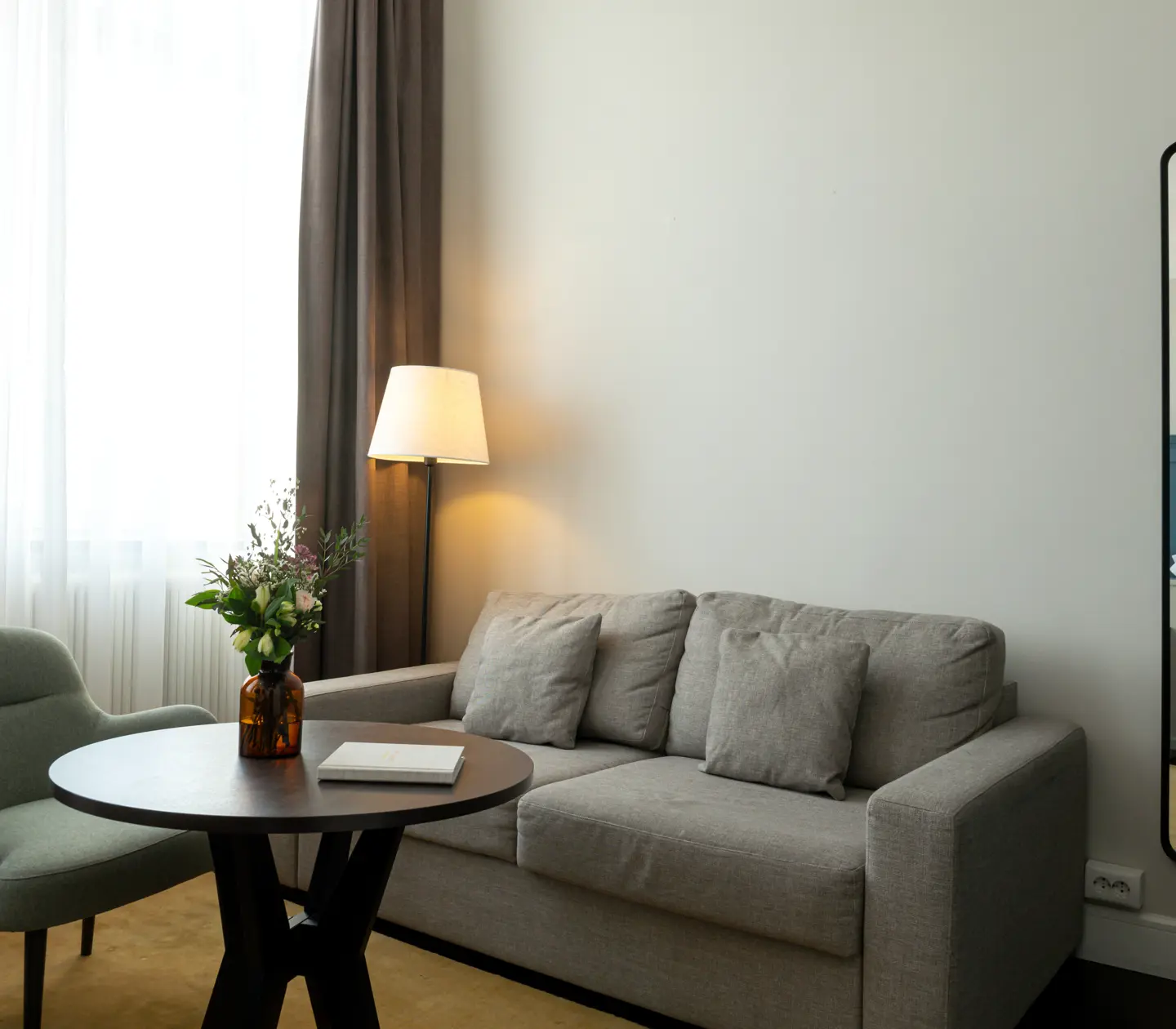 Bright hotel room with sofa group, mirror and window