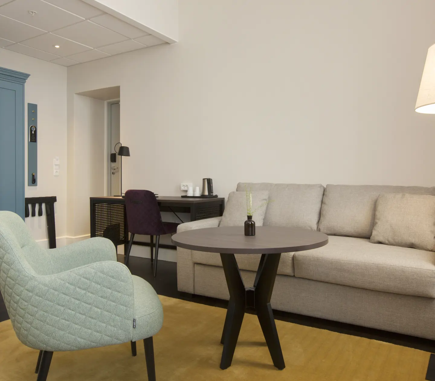 Bright hotel room with sofa group, desk and wardrobe