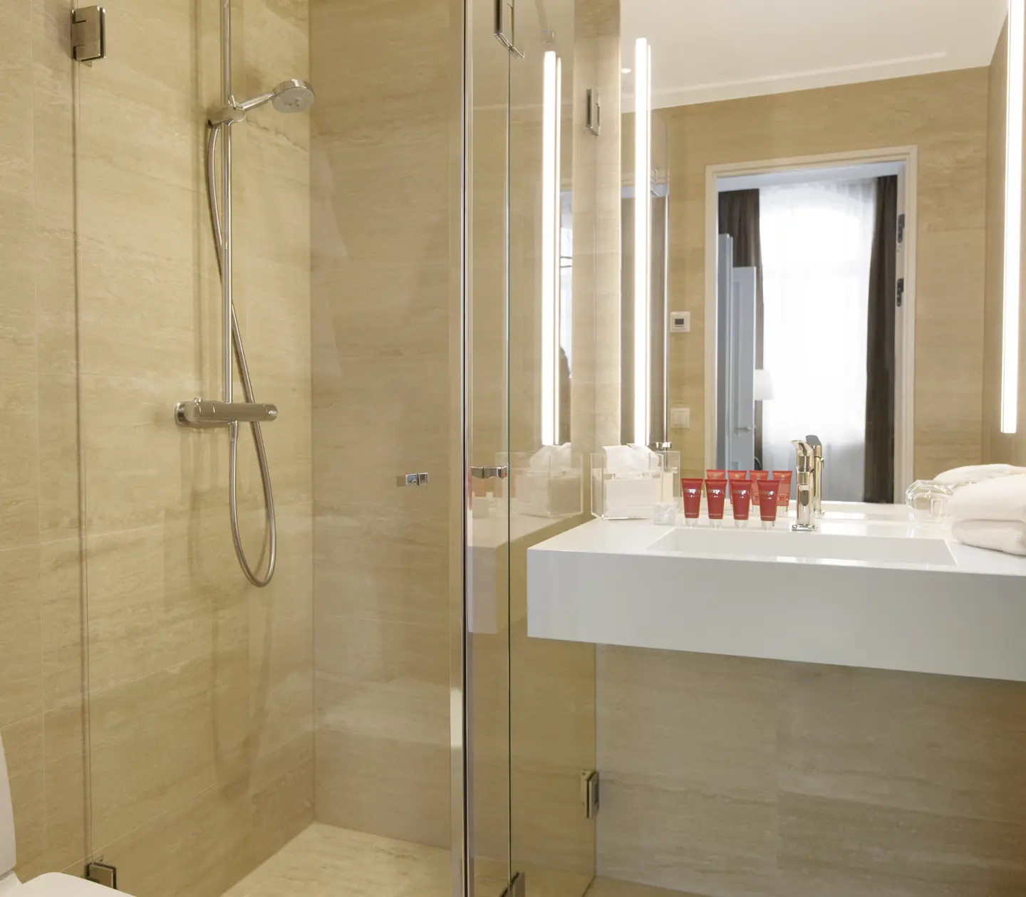 Beige bathroom with shower, sink and mirror