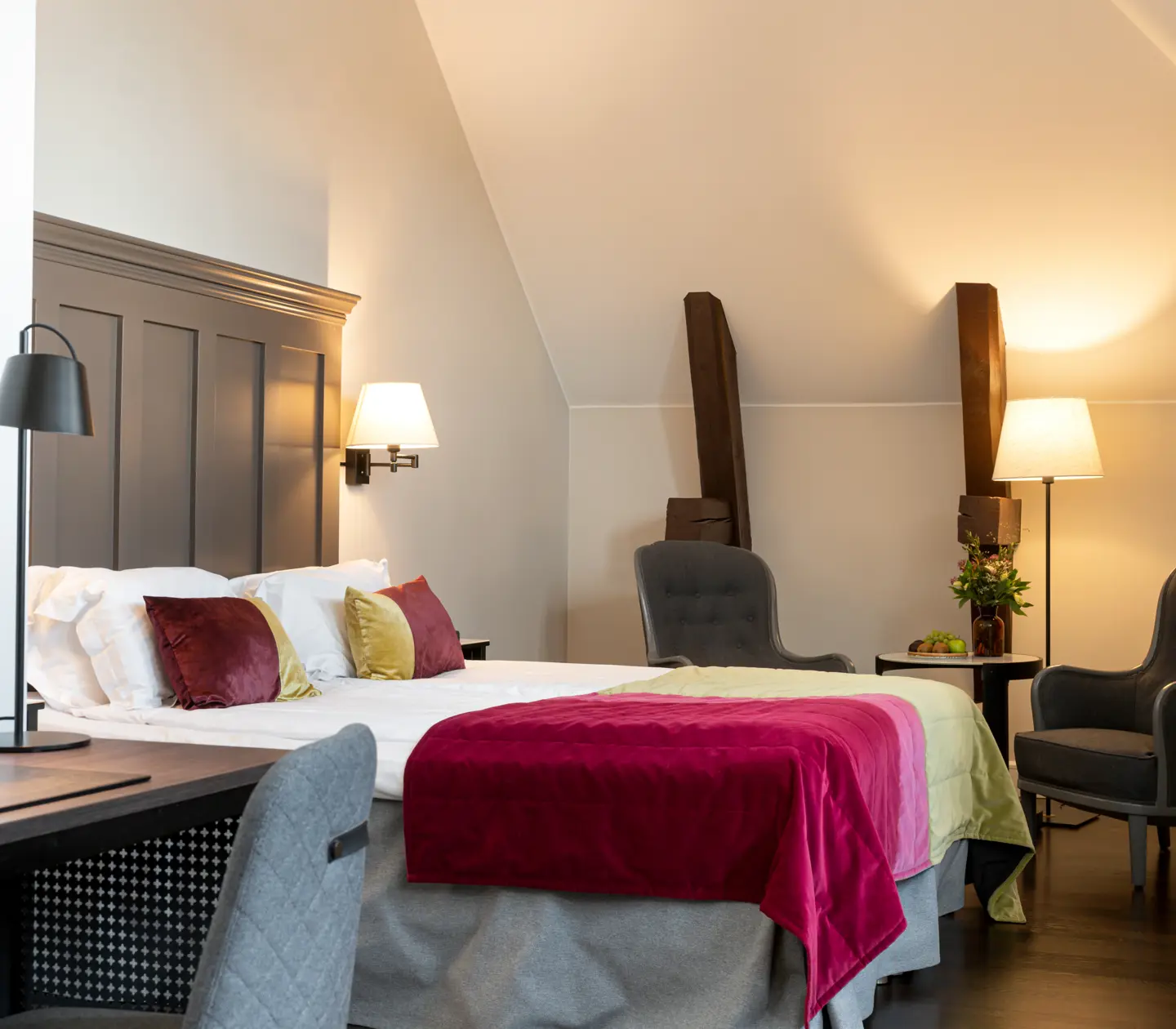 Bright suite with bed, large wooden headboard and armchairs