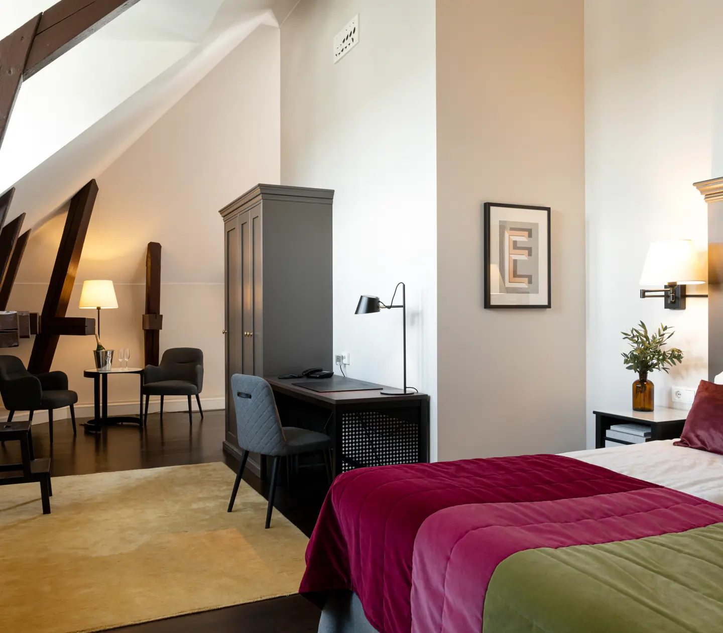 Bright suite with bed, desk and wooden beams