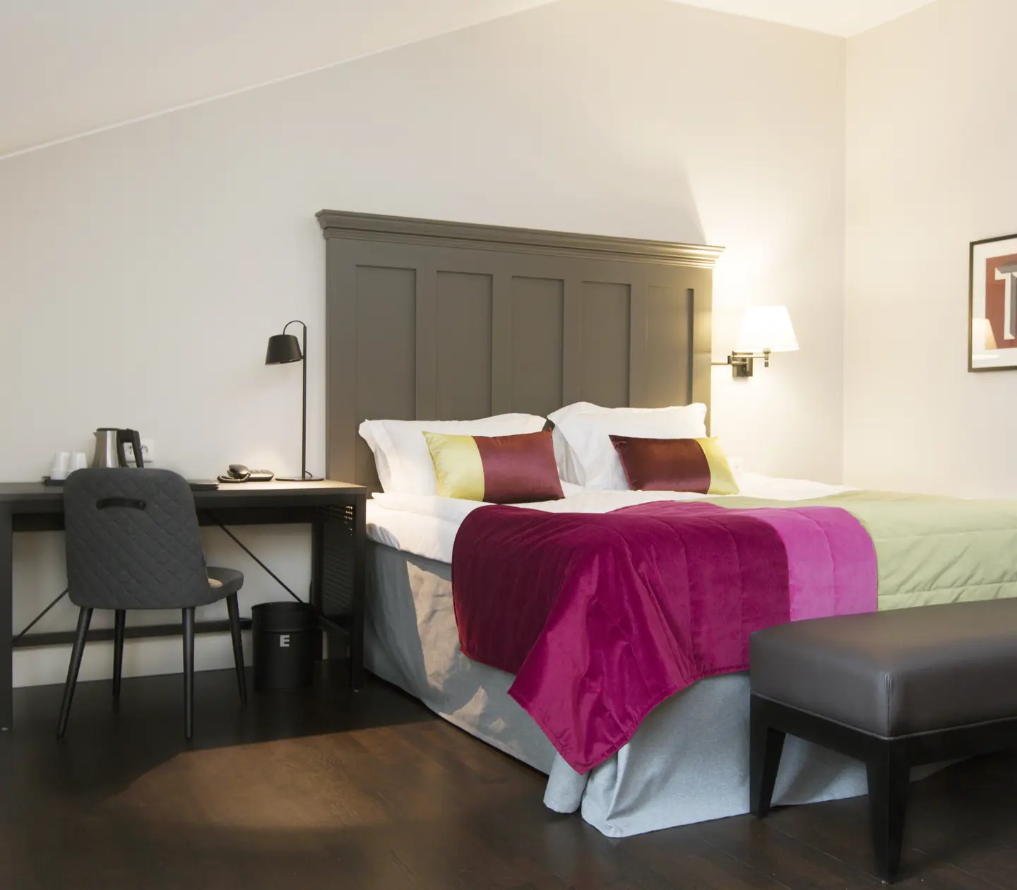 Bright suite with bed, large wooden headboard and desk