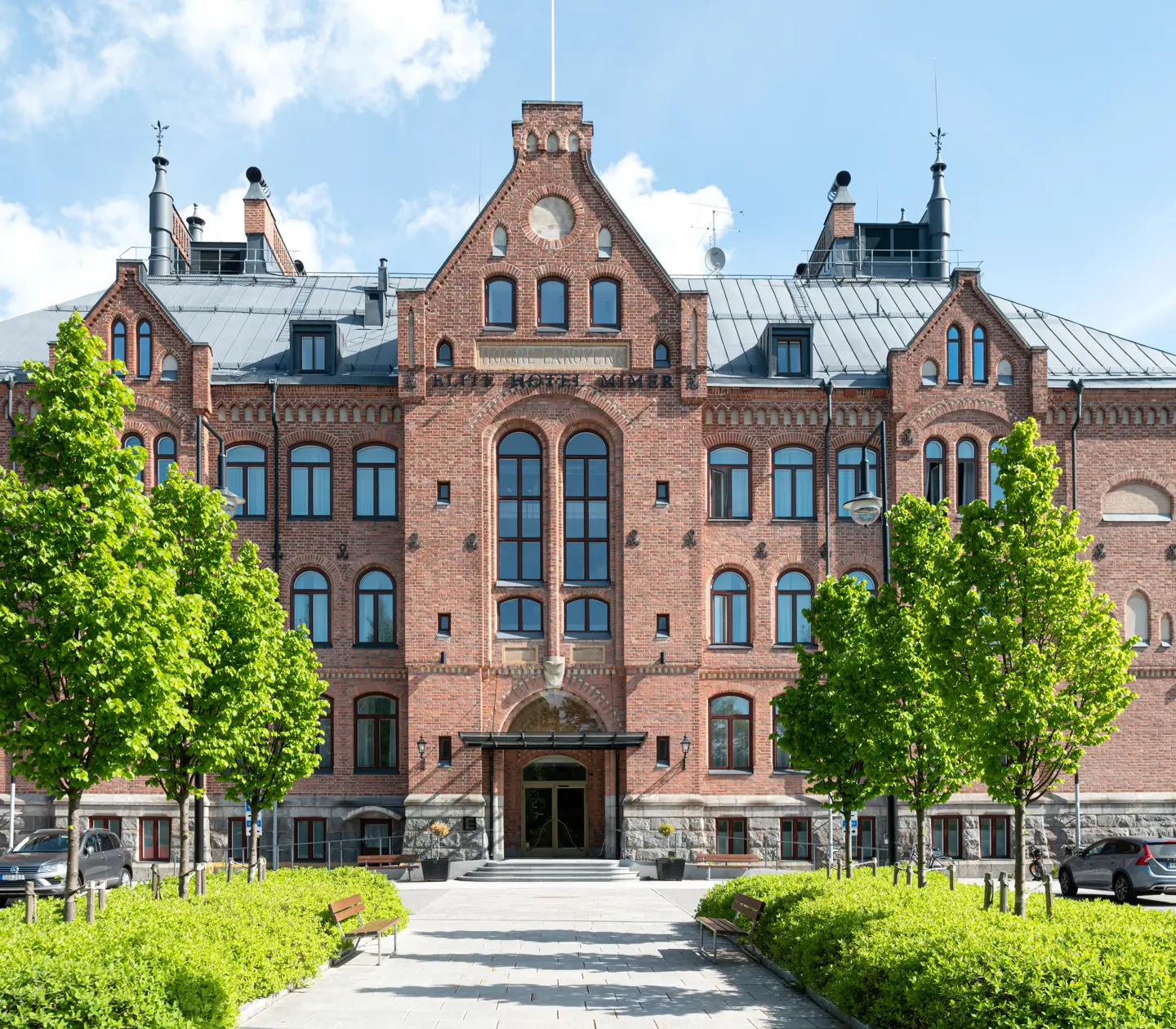 The grand brick facade of the Elite Hotel Mimer with trees in front