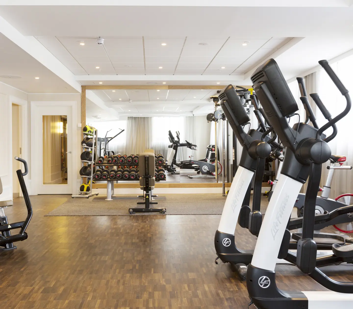 Gym environment with exercise machines, dumbbells and large mirror