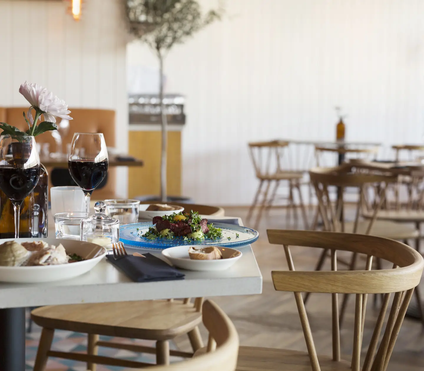 Restaurant environment with food and wine served on tables and food groups in the background