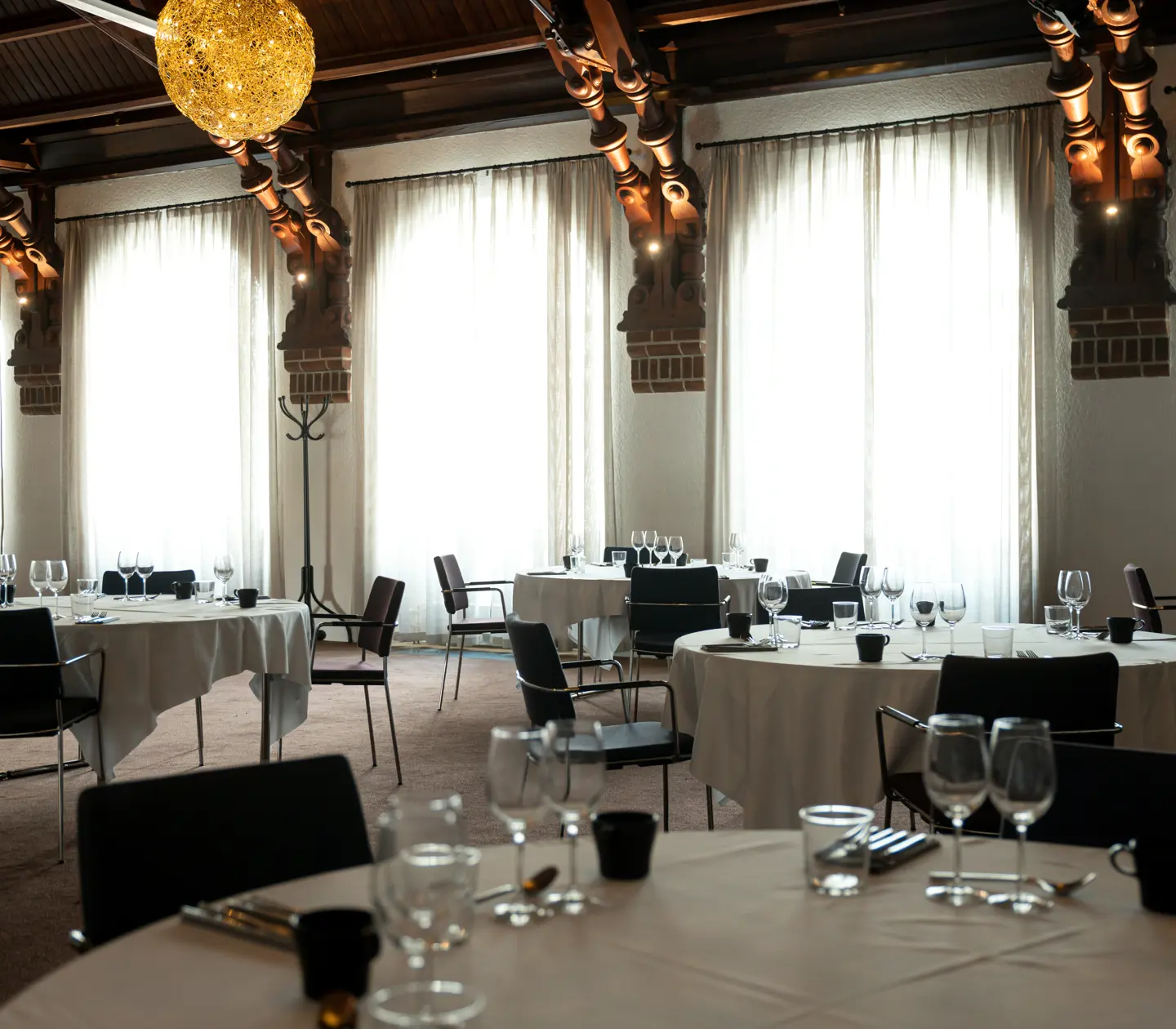Dining room with many windows, decorations and set round tables