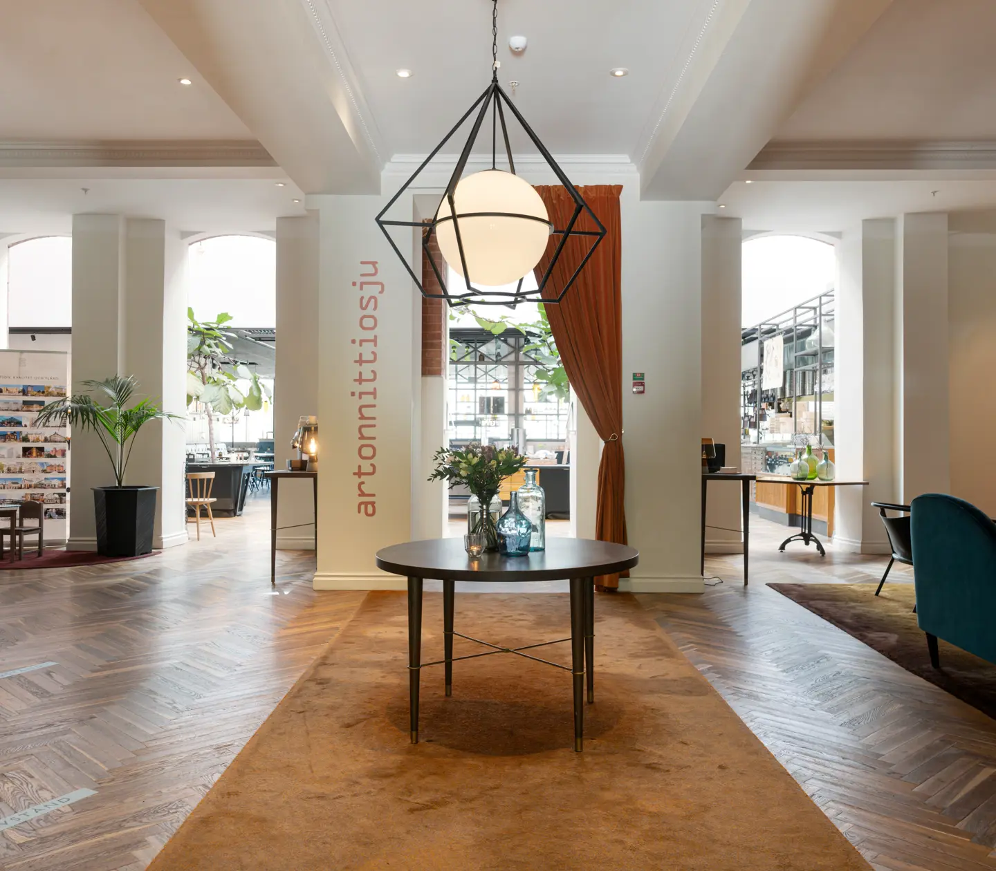 Hotel lobby with lounge furniture, reception desk and restaurant in the background