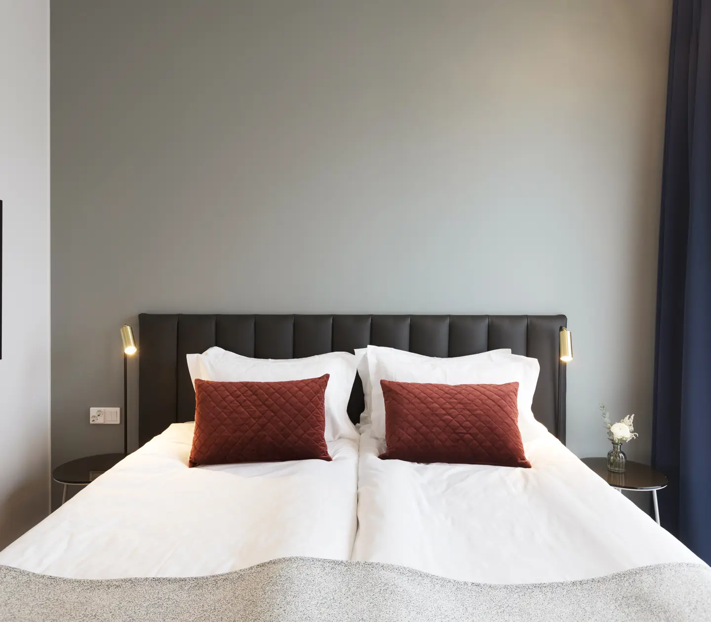 Bright hotel room with bed, dark headboard and small bedside lamps