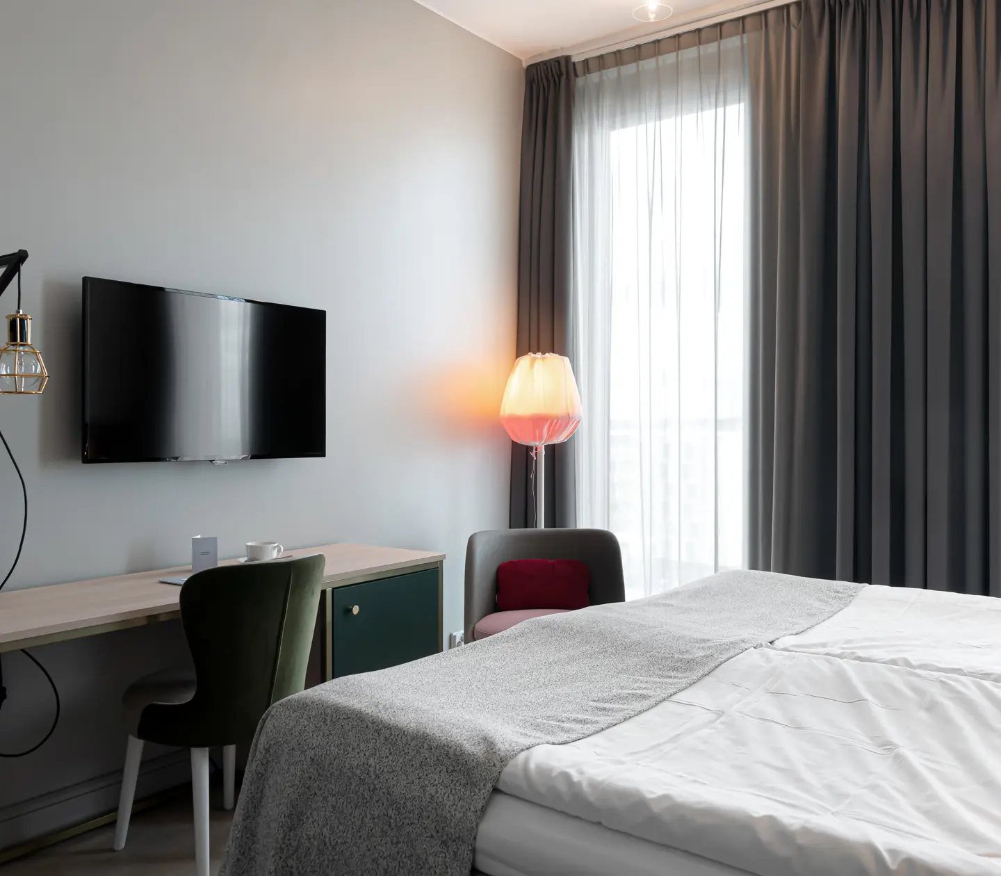 Bright hotel room with bed, desk and TV