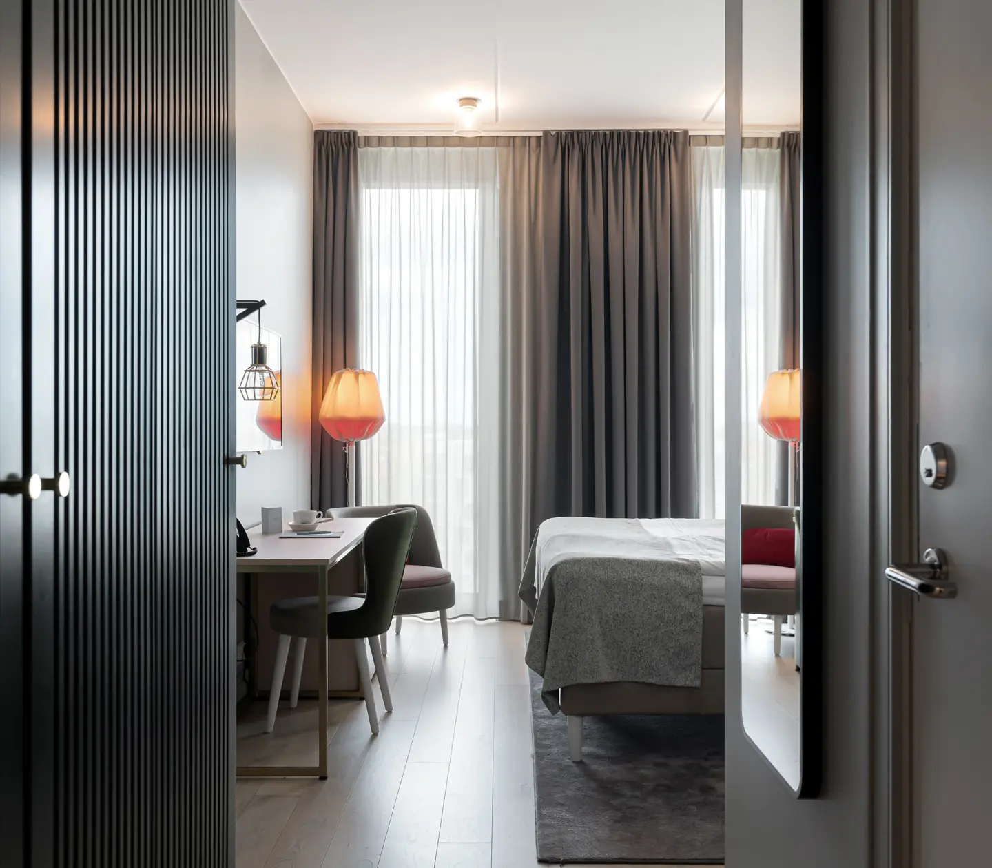 Bright hotel room with bed, desk and large window