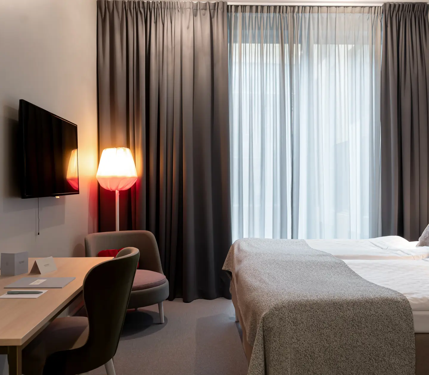 Bright hotel room with bed, desk and TV