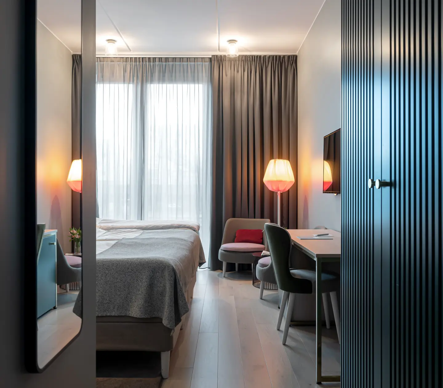 Bright hotel room with bed, wardrobe and desk