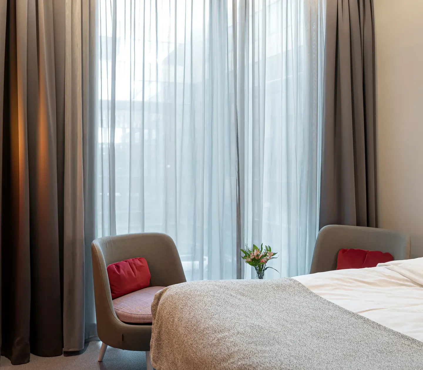 Bright hotel room with bed, large window and armchairs