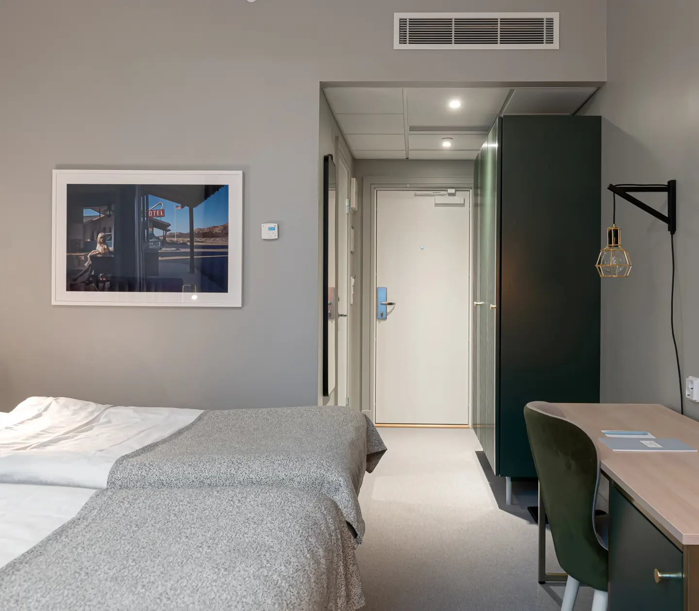 Bright hotel room with bed, desk and wardrobe
