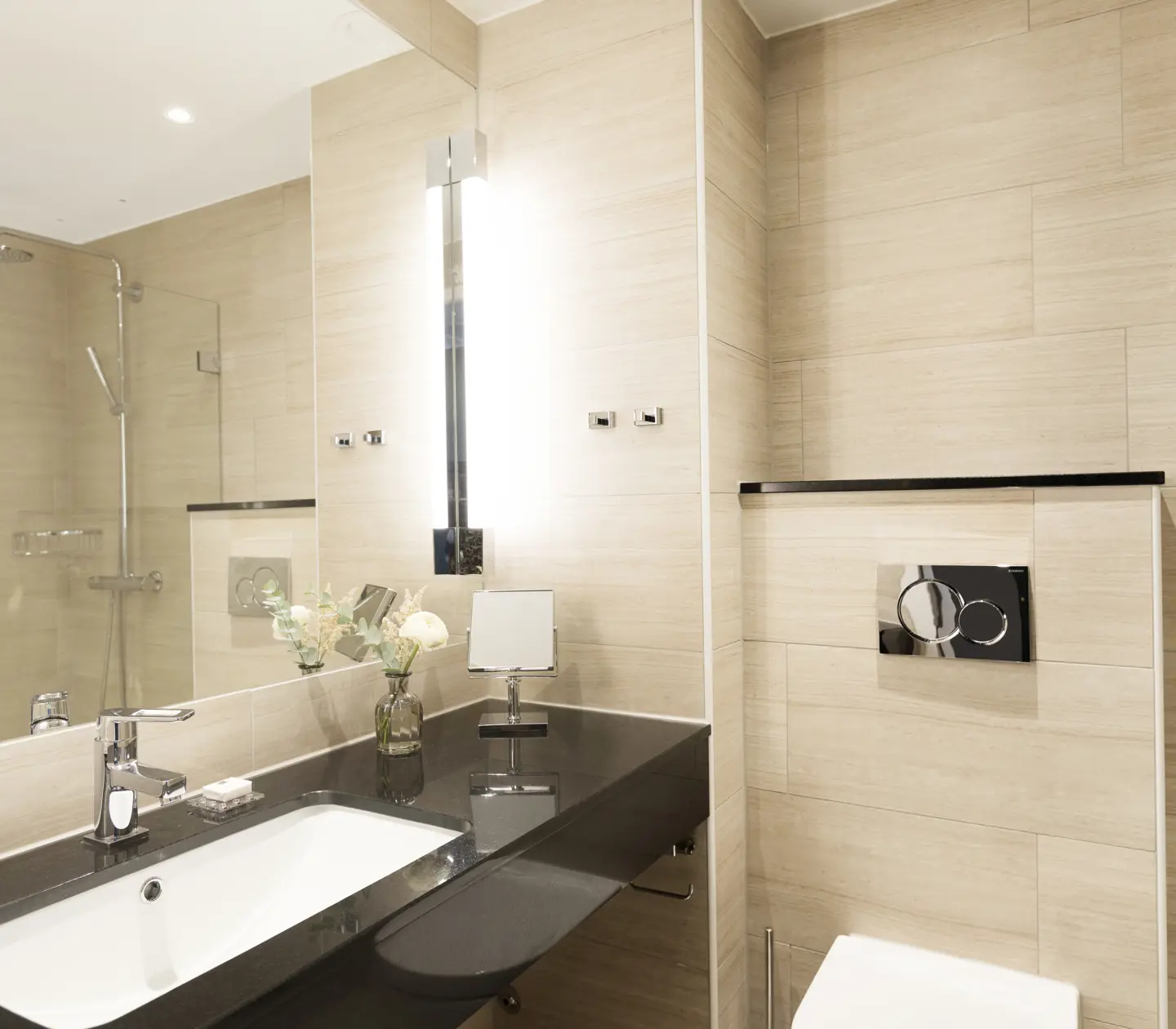 Beige bathroom with toilet, sink and large mirror
