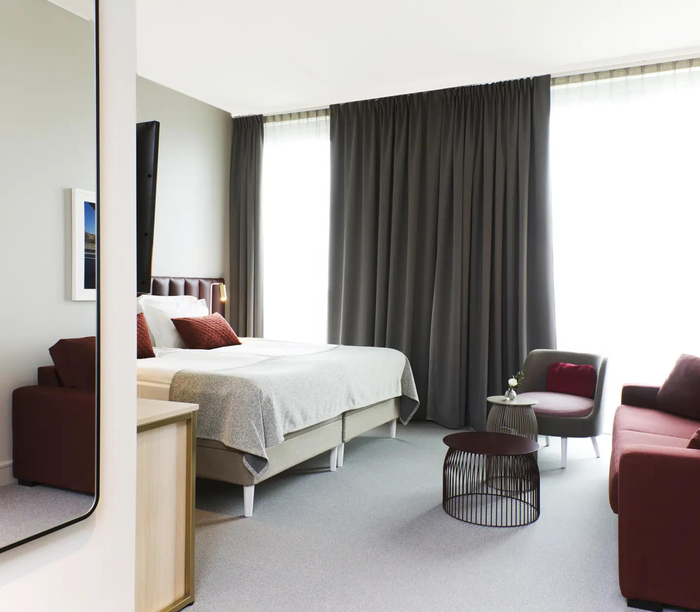 Bright hotel room with bed, red sofa and large window