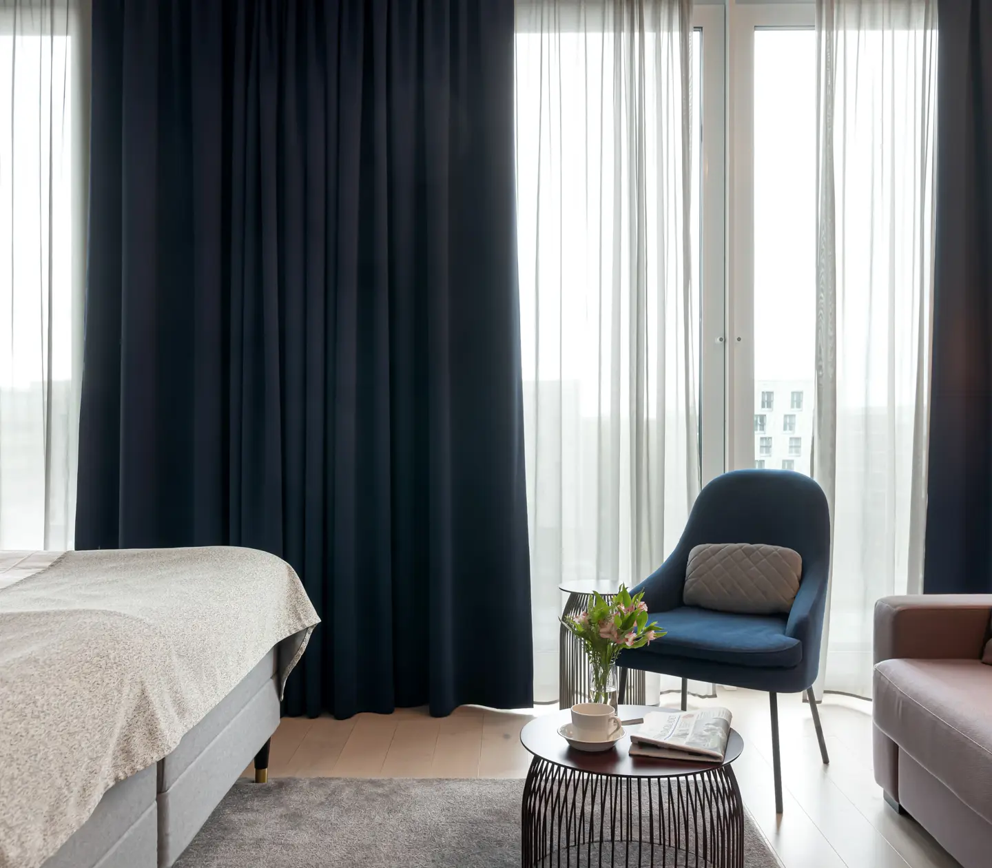 Cozy hotel room with sofa group, dark curtains and large window