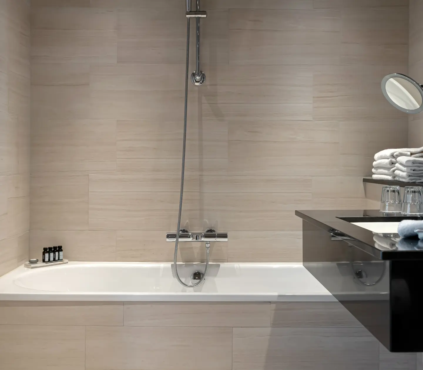 Beige bathroom with bathtub, towels and black sink