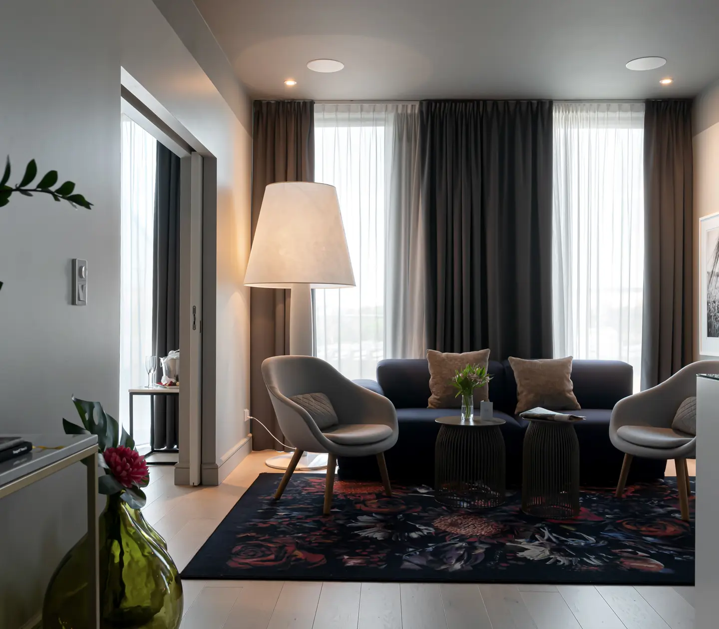 Cozy suite with large windows, sofa group and large floor lamp