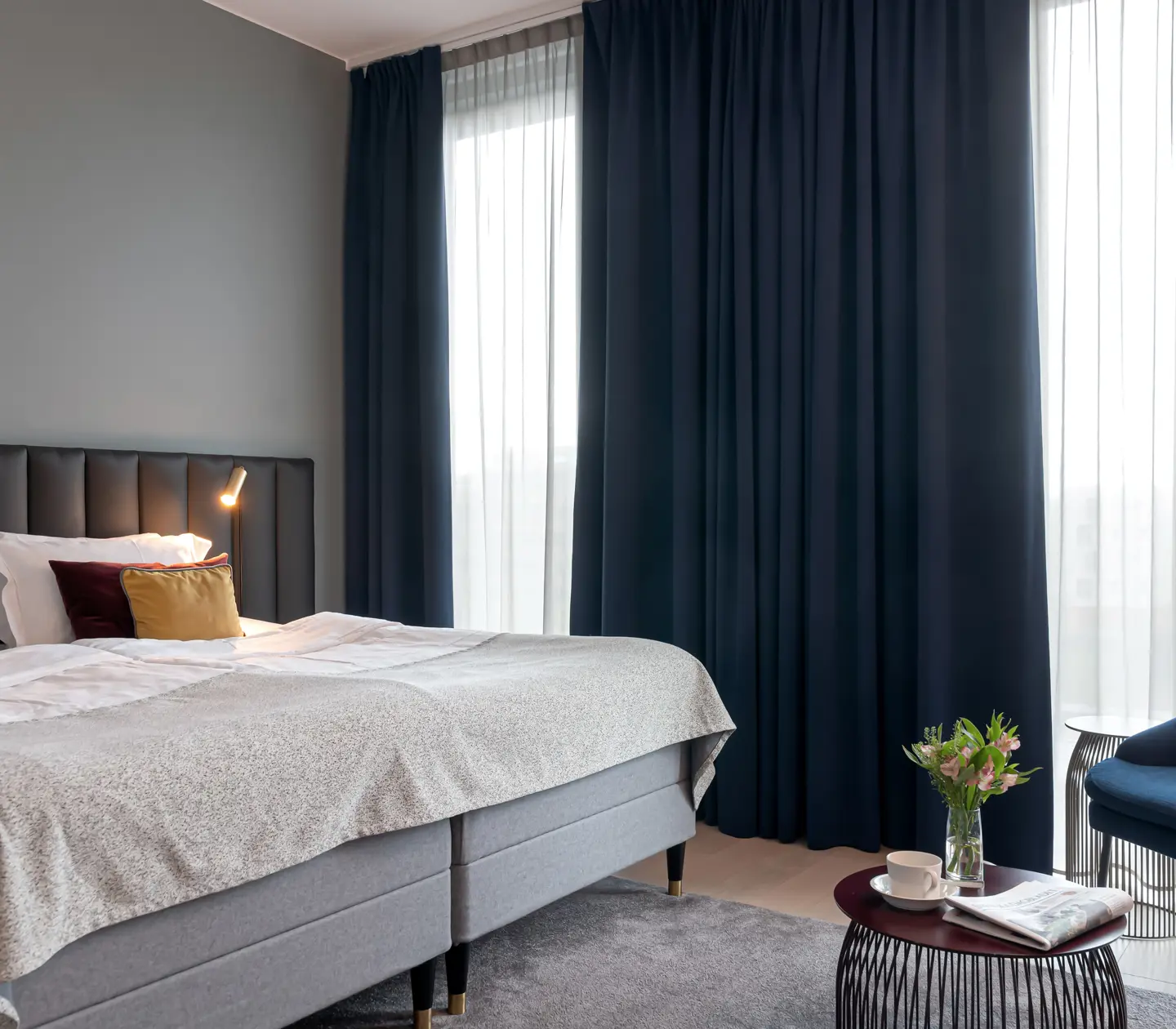Cozy suite with bed, dark headboard and large windows