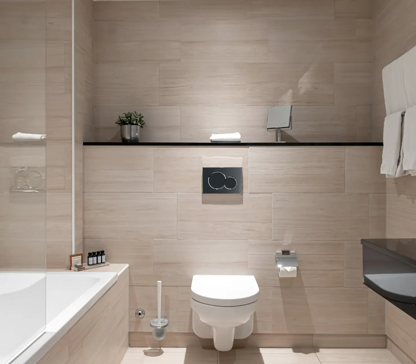 Beige bathroom with toilet, bathtub and towels