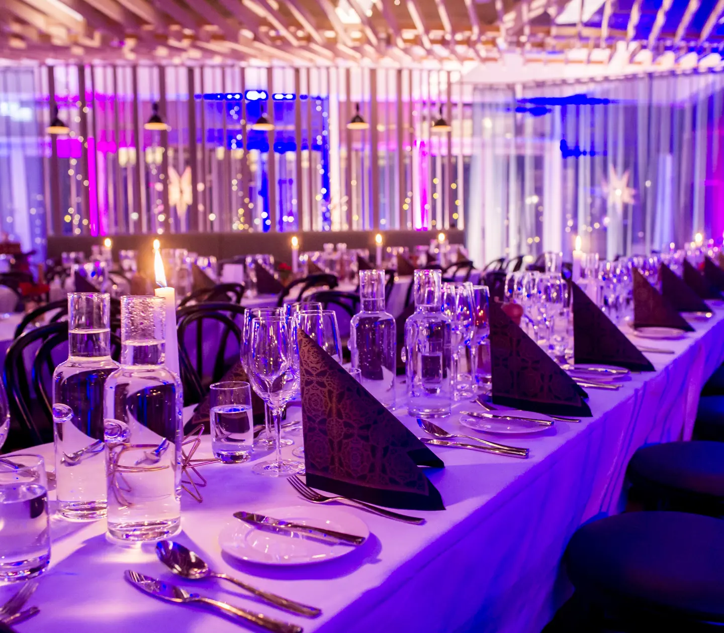 Restaurant environment with finely set long tables in subdued lighting