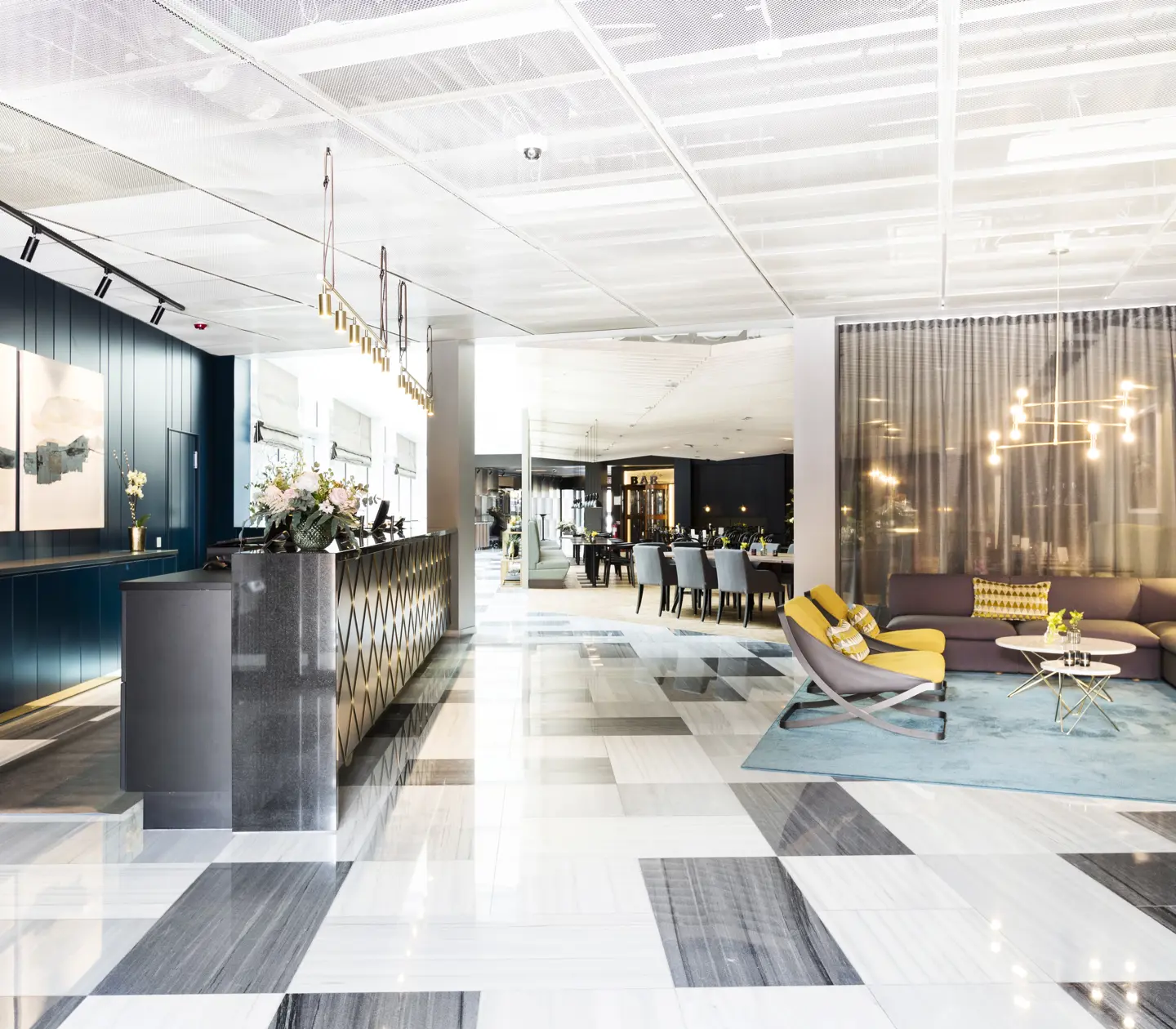 Hotel lobby with reception desk, lounge furniture and restaurant in the background