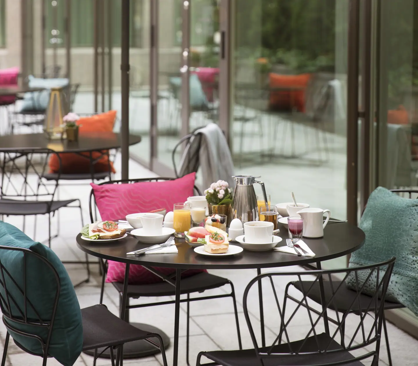 Outdoor dining with round tables, breakfast on the table and colorful cushions