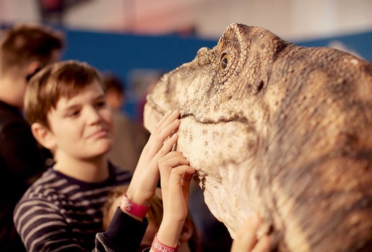 Ett barn rör vid en dinosaurie på Evolutionsmuseet i Uppsala