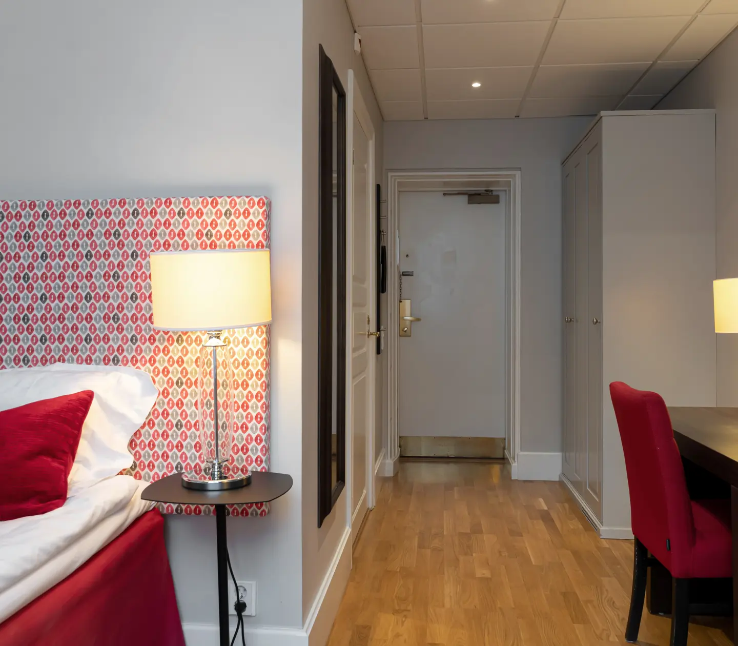 Hotel room with bed, desk and wardrobe