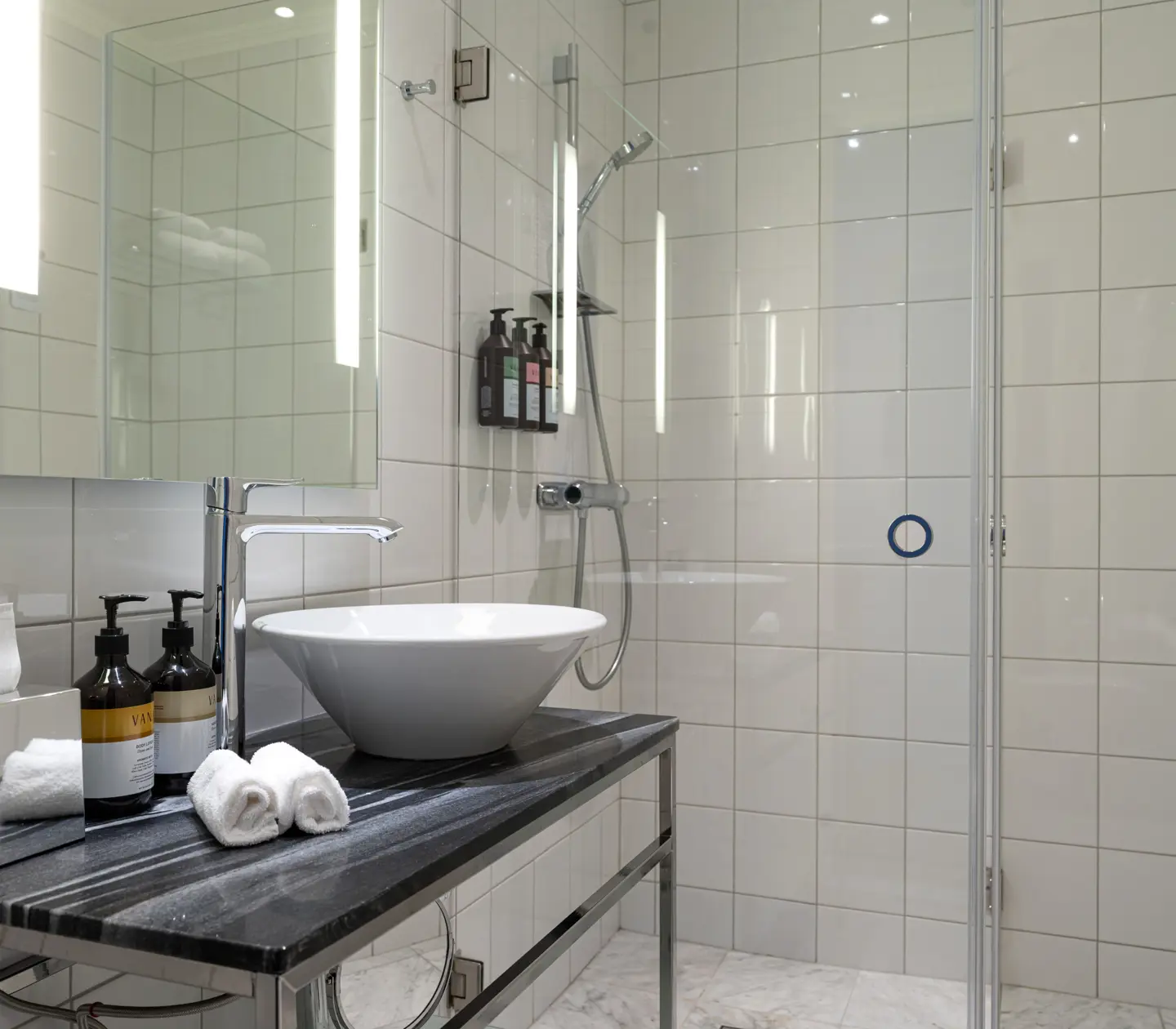 Modern bathroom with sleek countertop, white basin, and contemporary shower area.