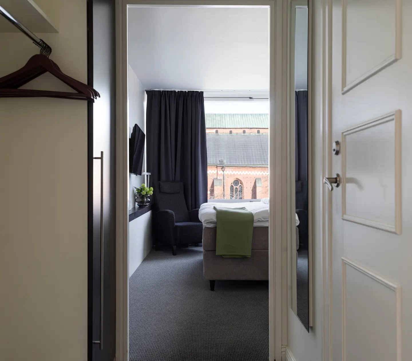 Mysigt hotellrum med skrivbord, spegel och garderob