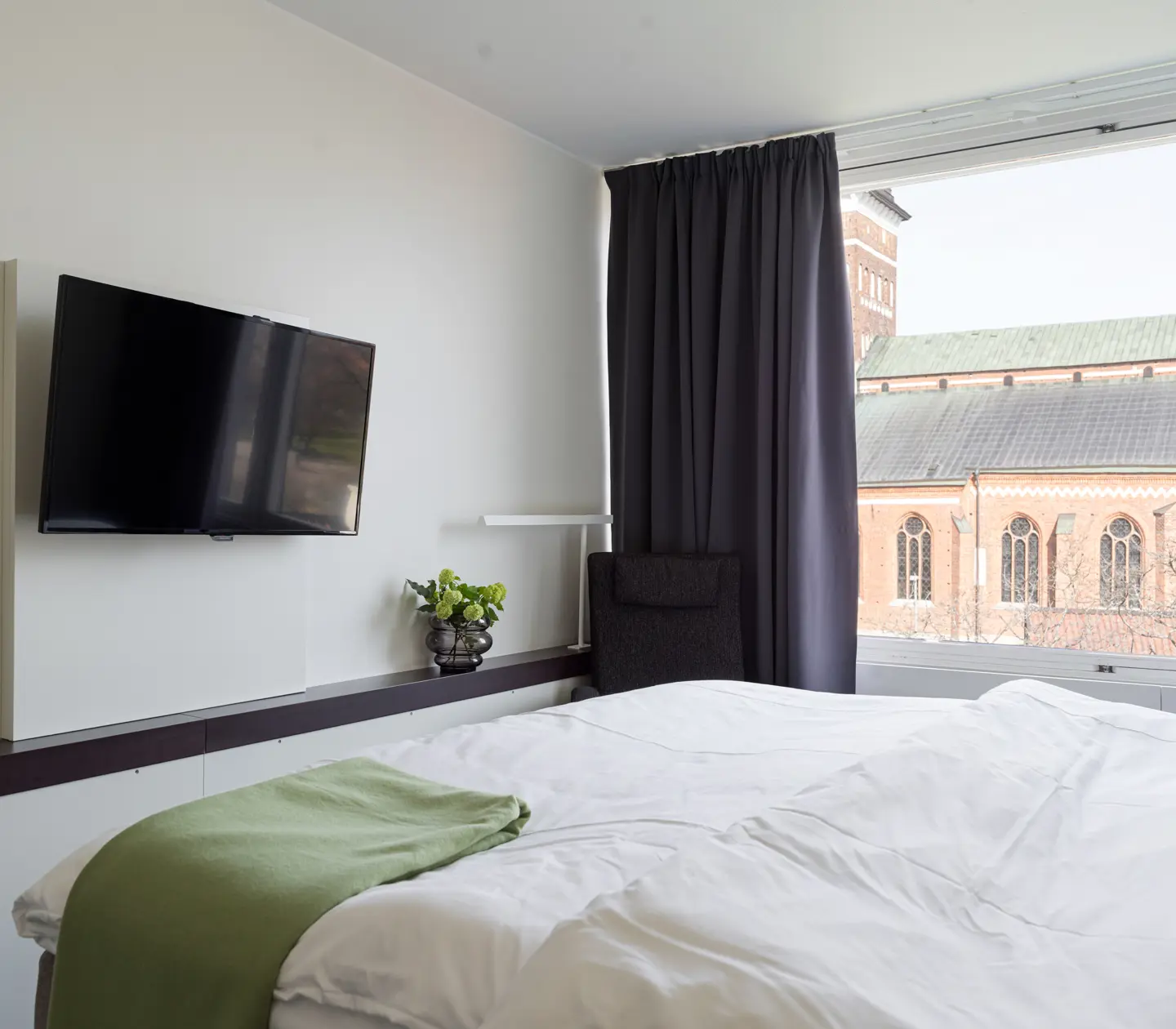 Mysigt hotellrum med säng, svart huvudgavel och sänglampa