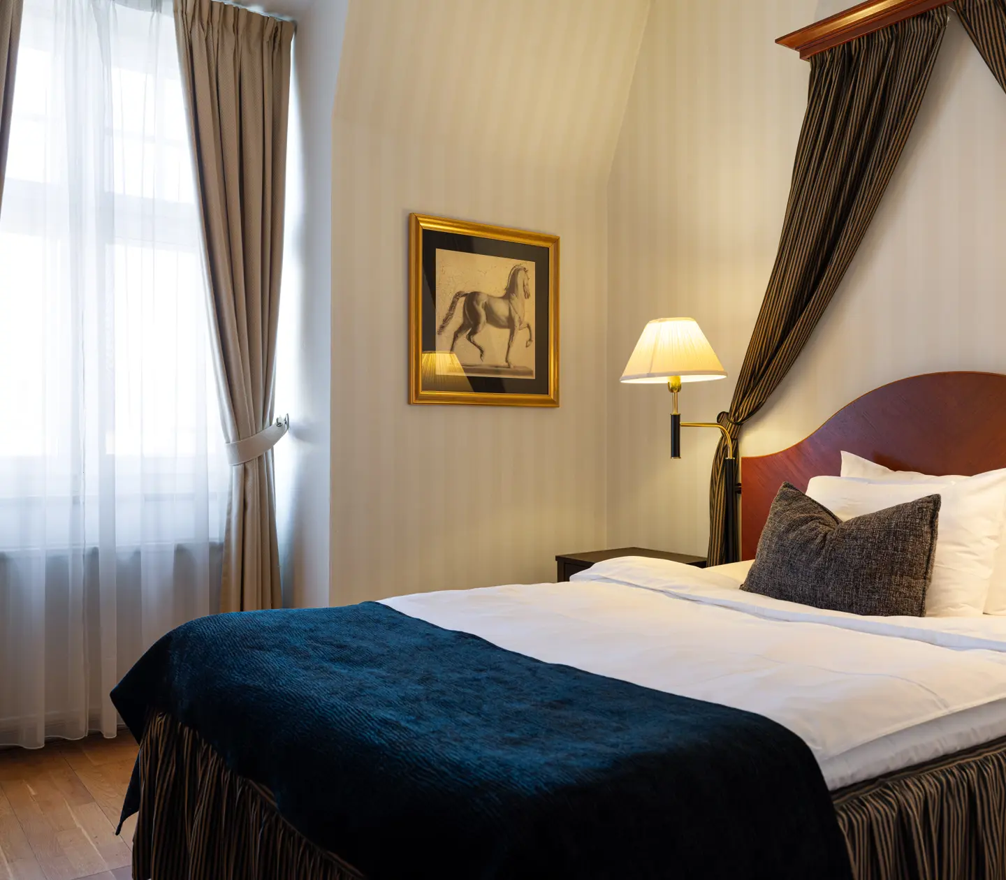 Elegant hotel room with cozy bed, plush pillows, dark blue throw.