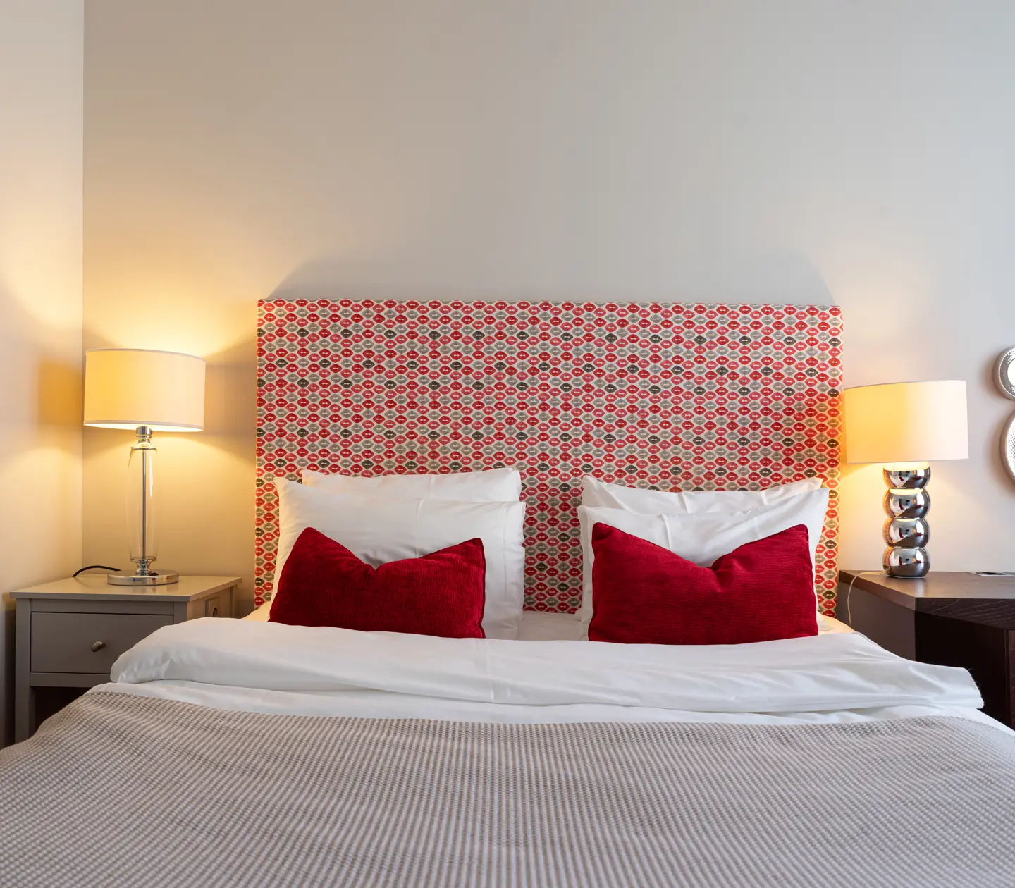 Hotel room with bed, bedside table and red-patterned headboard
